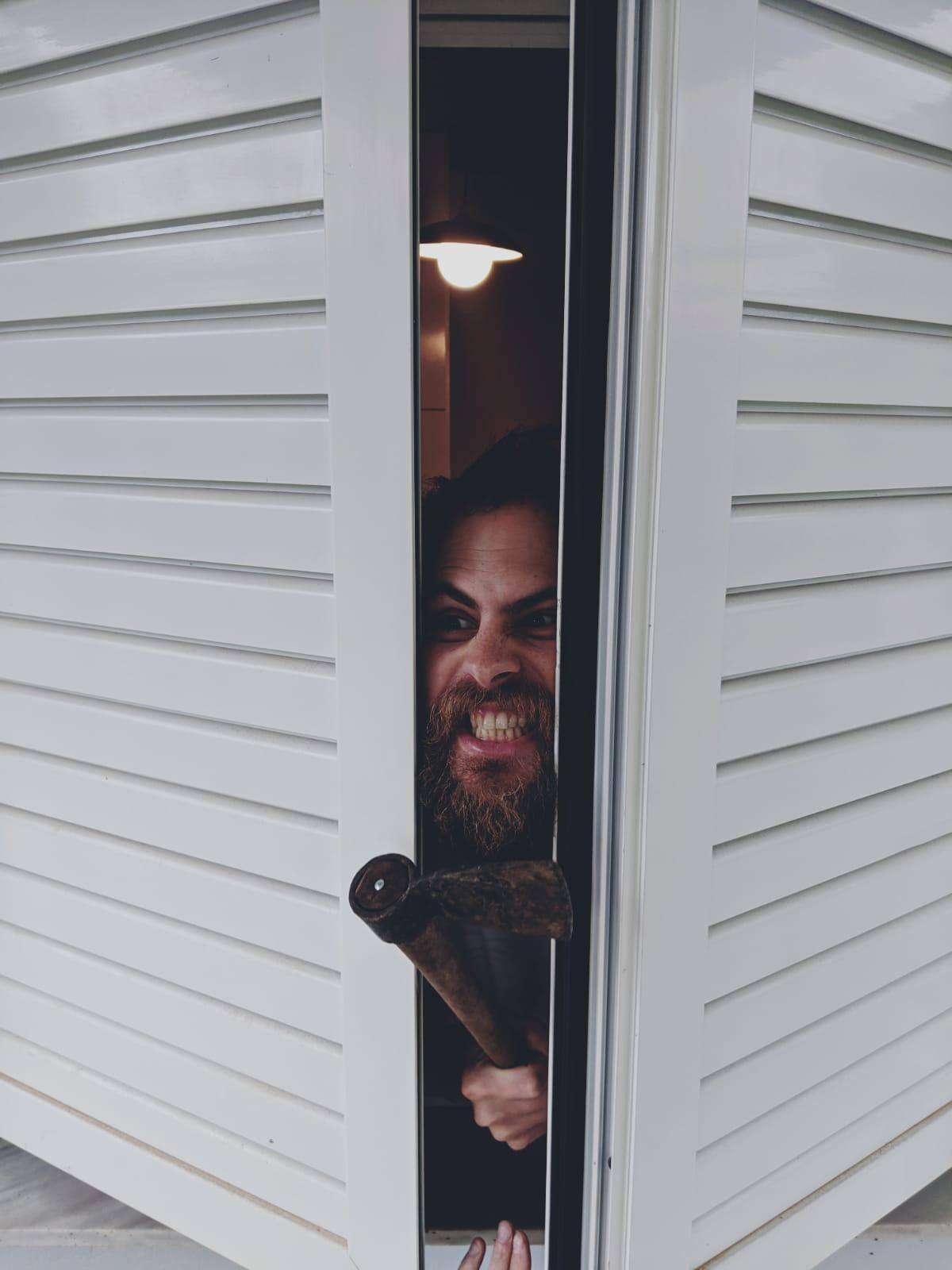 Man pushing face smiling in cupboard door